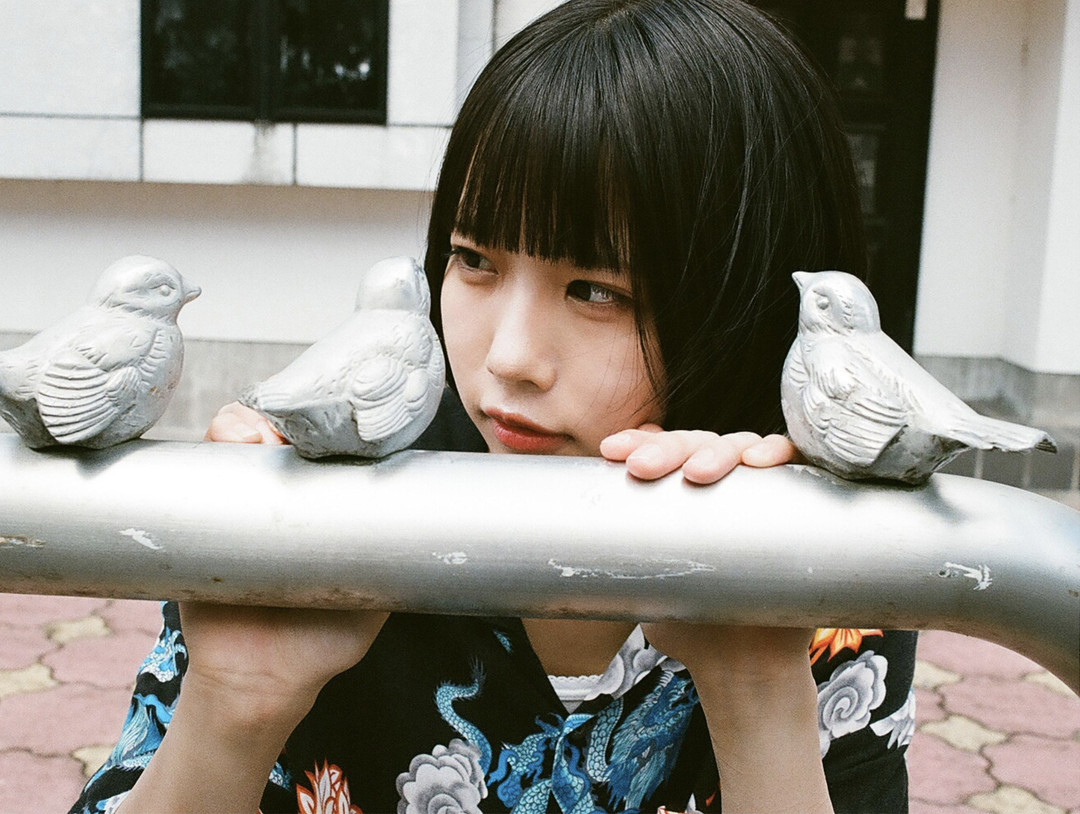 ano《ANOther》指宿編内页 · 公园栏杆后探身,脸挨着鸟形雕塑(跨页)